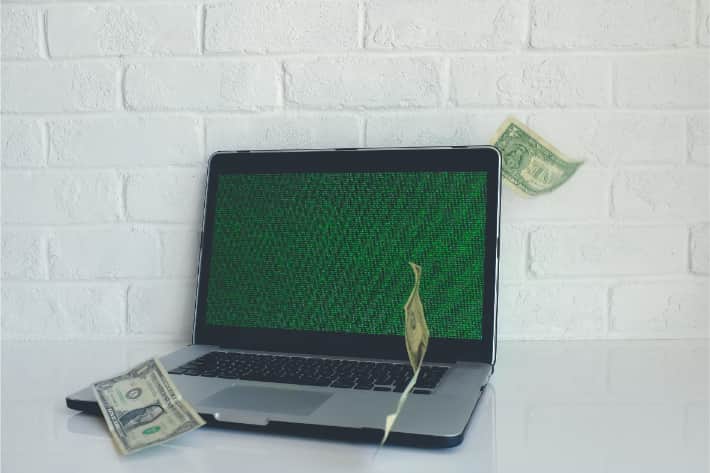 Hacked laptop with American dollar bills falling